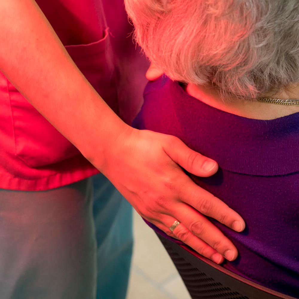 Una trabajadora del centro coloca su mano en la espalda de una residente